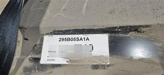 Dirty EV battery label after being wiped clean enough to read the visible part number and serial fields